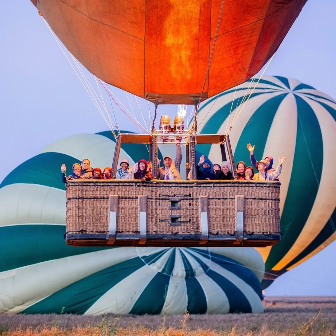 A fleet of Serengeti balloon safaris drifting over the savanna at dawn, highlighting the adventure's scale and view